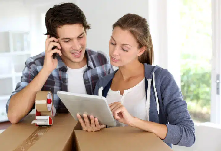 Two young people looking at a paper and speaking on the phone